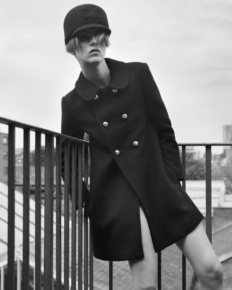 Model in black cap and coat leaning on metal railing outdoors for Crosscurrent Autumn/Winter 2024