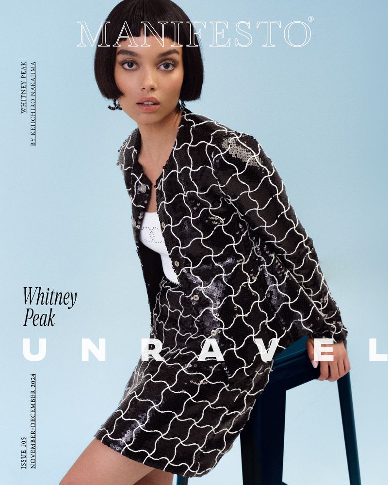 Whitney Peak wearing a patterned black and white sequin jacket seated on a blue stool against a light blue background