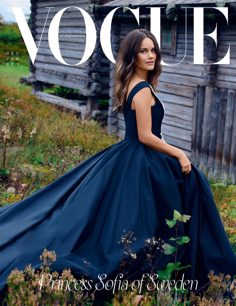 Vogue cover featuring Princess Sofia of Sweden in a navy gown, posing outdoors against a weathered wooden building and natural grasses.