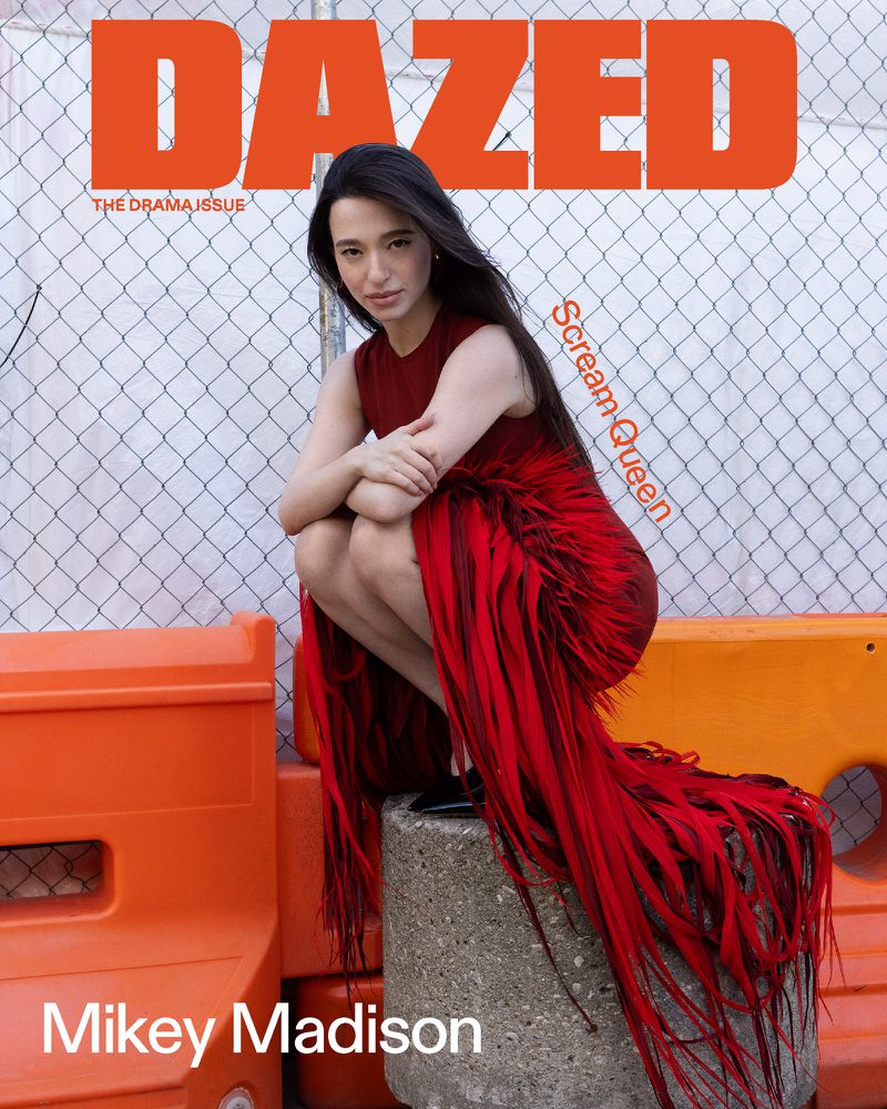 Magazine cover featuring Mikey Madison in a red fringed dress, kneeling against a chain-link fence, with 'Dazed' printed at the top.