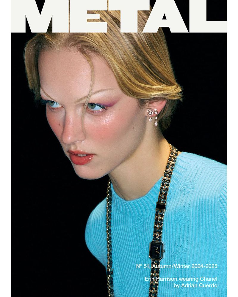 Magazine cover featuring a blonde woman with light pink makeup and a long black and gold Chanel necklace against a black background.