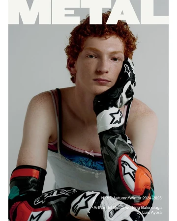 Magazine cover featuring a redhead model with freckles wearing motorcycle racing gloves, photographed indoors with a neutral background.