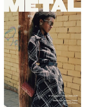 Model Metta Irebe leaning against a wooden post wearing a plaid coat and sunglasses for METAL Magazine