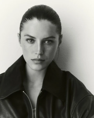 Portrait of a woman wearing a black leather jacket with a high collar against a plain white background