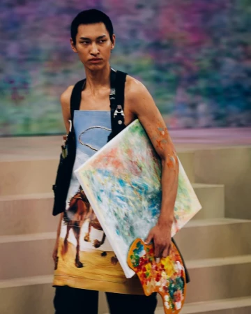 Model holding a painted canvas and artist palette wearing an apron with a landscape print for ADSB Andersson Bell in Shanghai