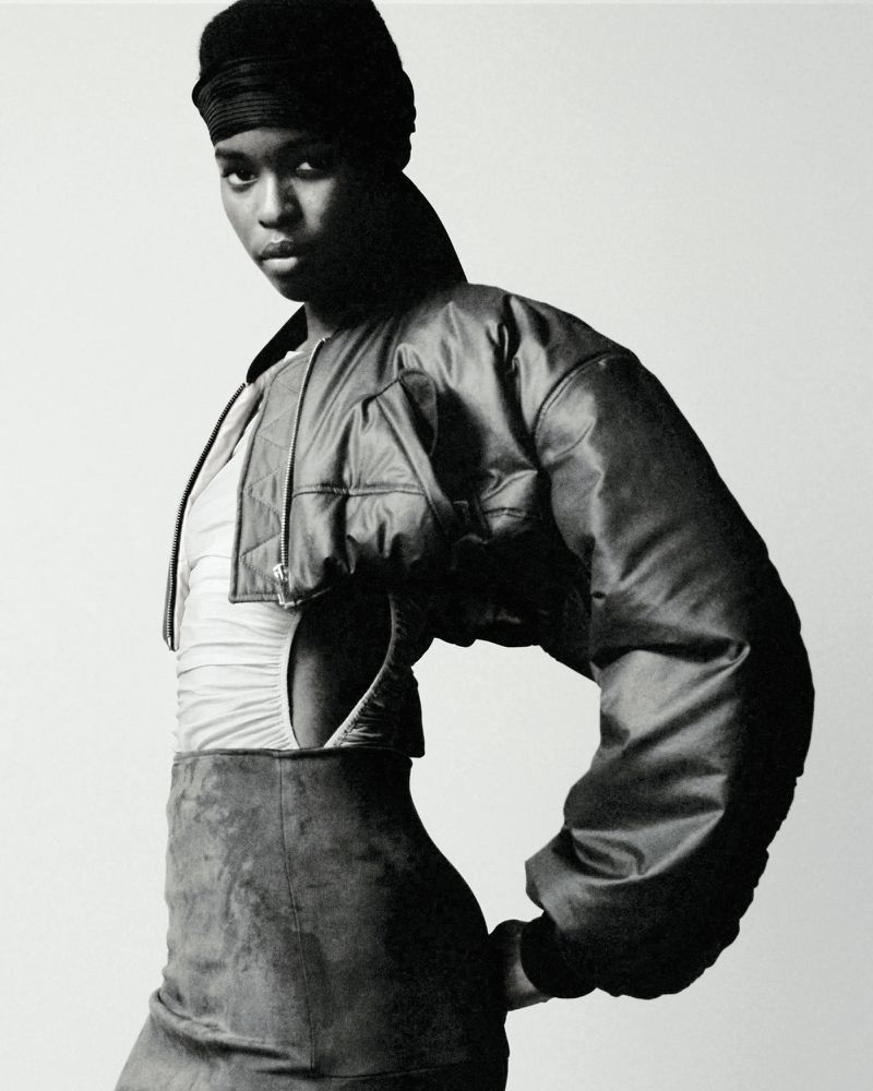 Model wearing a cropped dark bomber jacket and headwrap in a black and white backstage photograph for Atlein SS25.