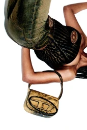 Model viewed from above wearing a striped top, washed jeans, and holding an acid-wash Diesel shoulder bag against white.