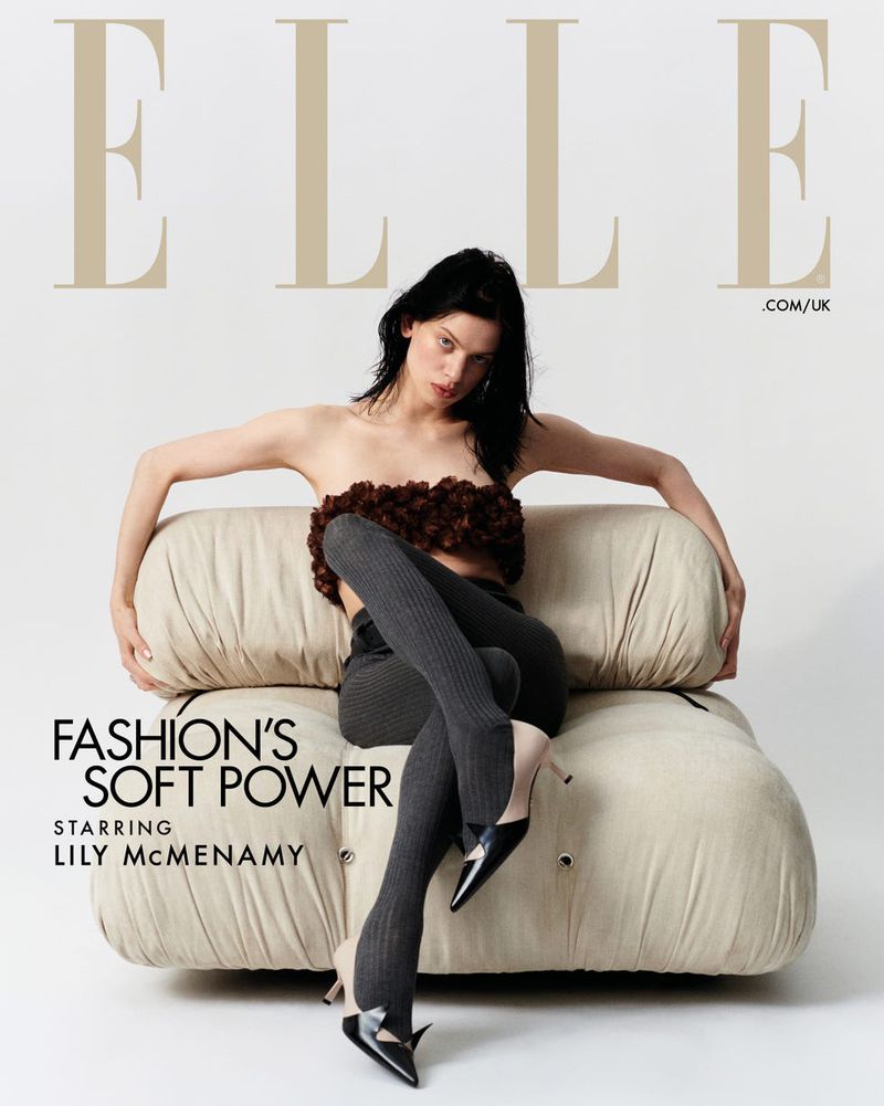 Elle magazine cover featuring Lily McMenamy seated on a cream sofa wearing a brown floral top, gray tights, and black pointed heels.