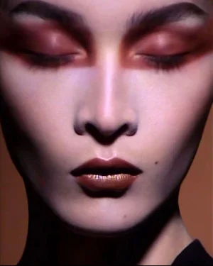 Close-up beauty portrait of model Bismuth Arsenide with dramatic blended eyeshadow and metallic lips with eyes closed.