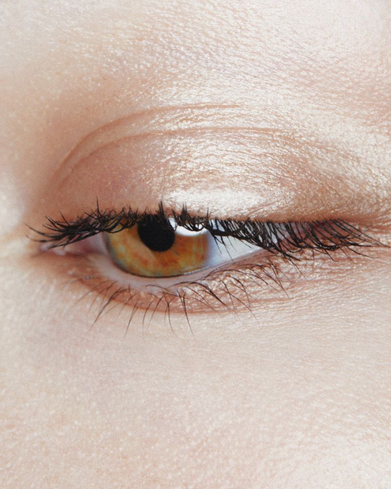 Close-up studio shot of an adult female's eye, showcasing makeup on the eyelid, defined lashes, and fair skin tone with subtle shadow.