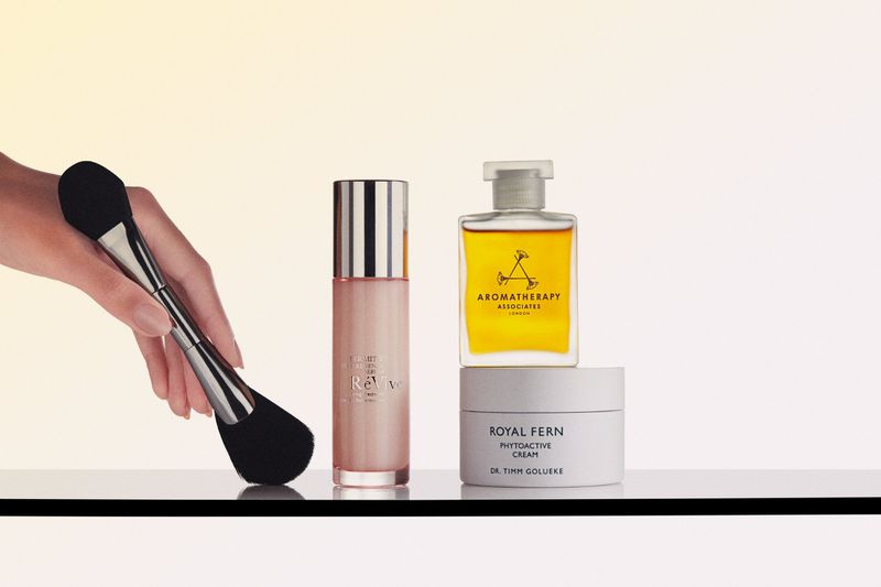 Cosmetic product arrangement featuring a makeup brush, skincare serum, oil, and cream on a white surface, ideal for beauty campaigns.