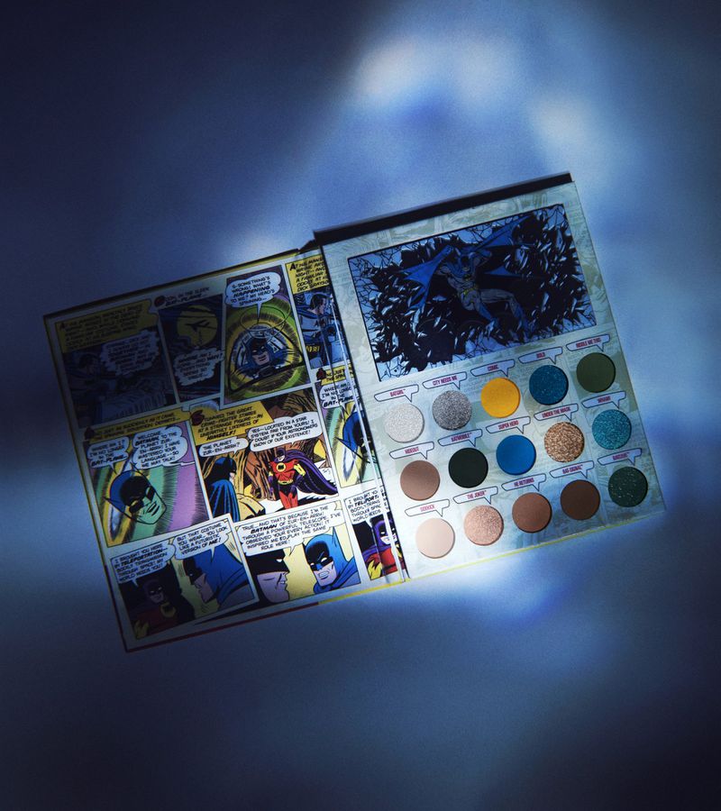 Open Batman comic-themed eyeshadow palette displaying colorful shadows, comic art pages, vibrant hues, and dramatic lighting.