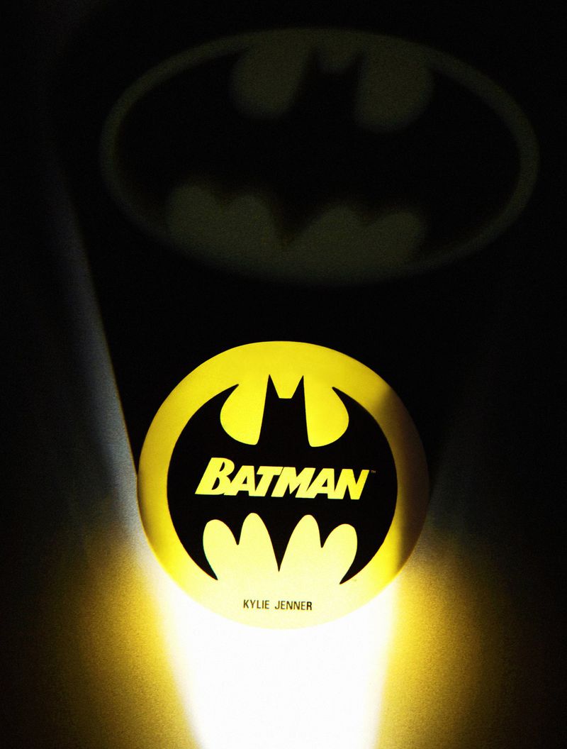 Batman logo merchandise with yellow and black design and shadow in a dark setting with Kylie Jenner branding.