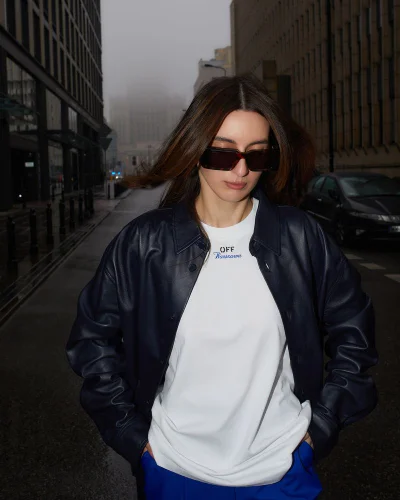 Woman wearing a dark leather jacket over a white t-shirt and sunglasses on a wet street