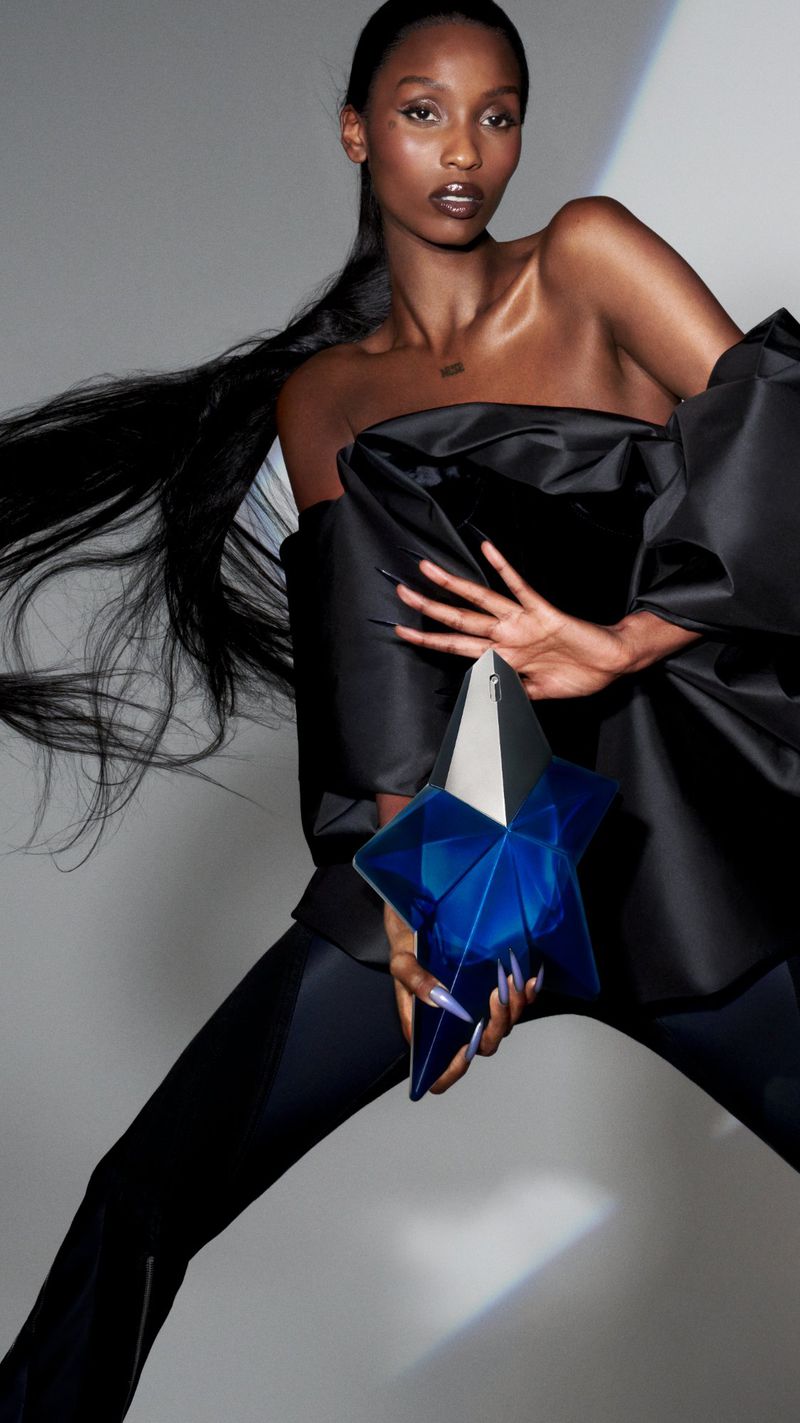 A striking fashion portrait captures a poised African American woman in a black off-shoulder dress holding a unique blue geometric clutch.