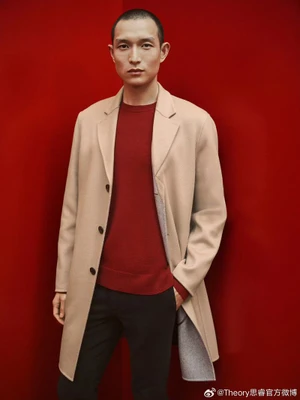 Model Zhang Wenhui in a camel coat and red sweater against a bold red wall for the Theory Lunar New Year 2024 campaign.
