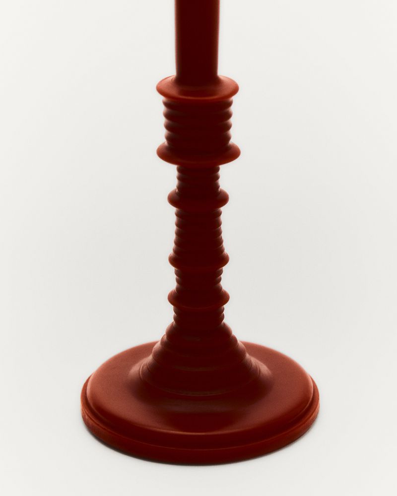 Elegant, red candlestick holder against a white background, showcasing its unique design and simple beauty.