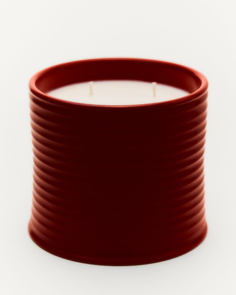 Studio shot of a red cylindrical candle with a ribbed texture on a white background, highlighting the candle's modern design.