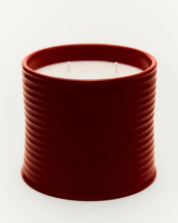 Studio shot of a red cylindrical candle with a ribbed texture on a white background, highlighting the candle's modern design.