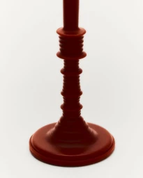 Terracotta red sculpted wax candlestick base standing upright against a bright white seamless background.