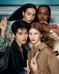 Four diverse models posing closely together while holding Gucci Concentré de Beauté concealer tubes in a studio campaign.