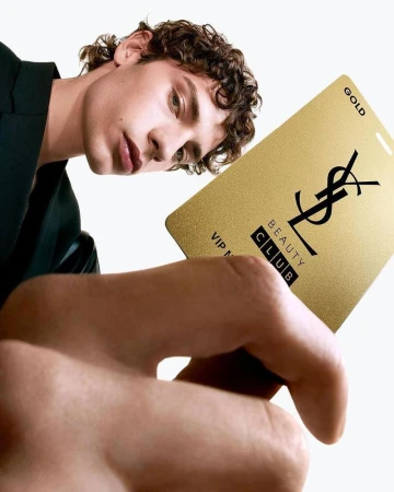 Man holding a gold YSL Beauty Club VIP card in a close-up shot, isolated against a white background, showcasing beauty industry branding.