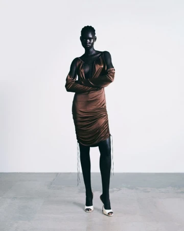 Model wearing a brown satin ruched dress with matching sleeves standing against a plain light background