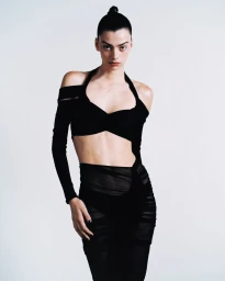 Model wearing a black cutout top and ruched skirt against a plain white background for Atlein