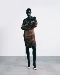 Model wearing a brown satin ruched dress with matching sleeves standing against a plain light background