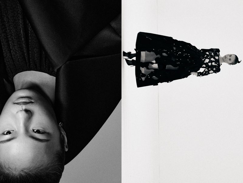 High-contrast black and white fashion shot of two women, one in close-up, the other in a long black gown, against a white backdrop.