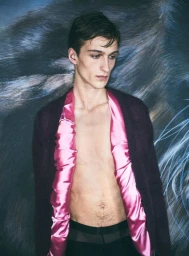 Model wearing a dark cardigan with pink satin lapels against a painted backdrop of a wolf for J.W. Anderson