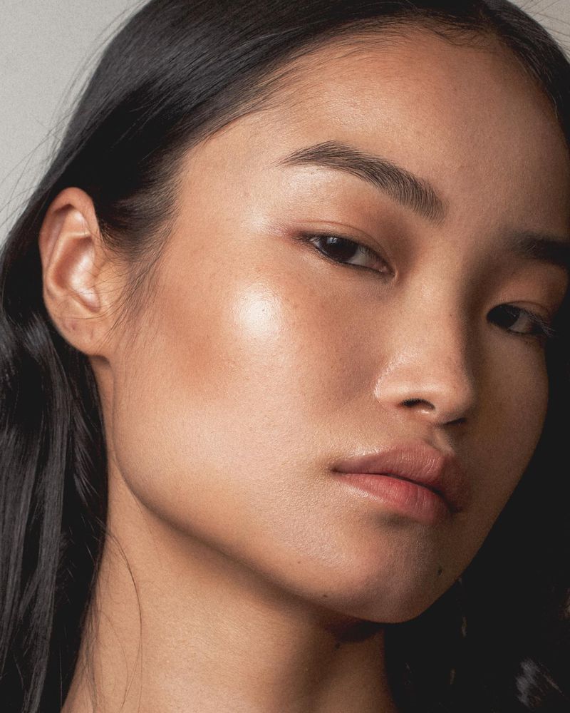 Close up portrait of a model with dark hair and natural makeup against a plain background for Christopher Esber