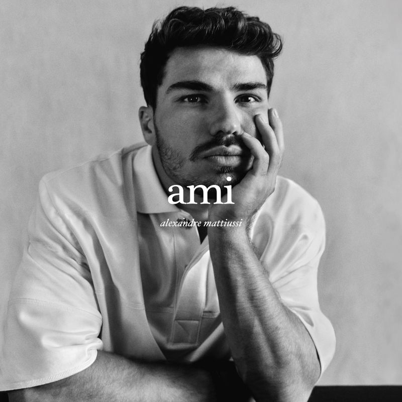 Portrait of a light-skinned adult male with dark hair, facial hair, and a casual shirt in a black-and-white studio photograph.