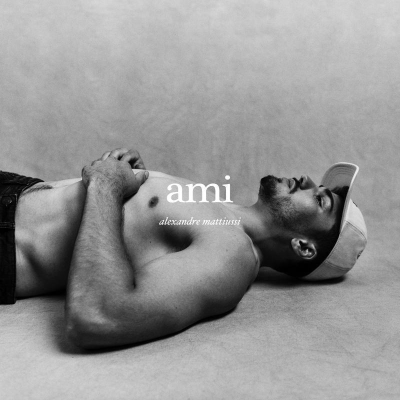 Monochrome portrait of athlete Antoine Dupont lying down wearing a baseball cap against a textured background