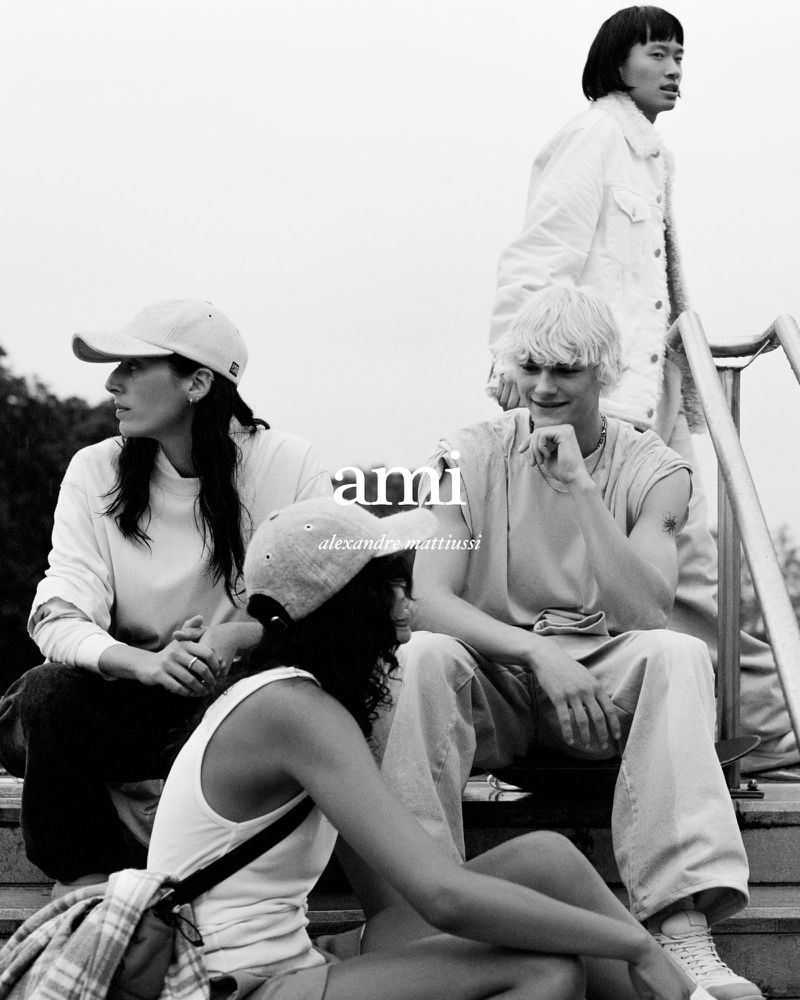 Four young adults in casual apparel pose on outdoor steps, captured in a monochromatic fashion editorial style for Ami Alexandre Mattiussi.