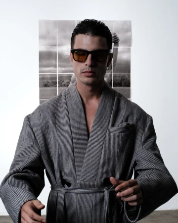 Portrait of a man in a striped robe and sunglasses, posing in front of a nine-panel black and white landscape photo.