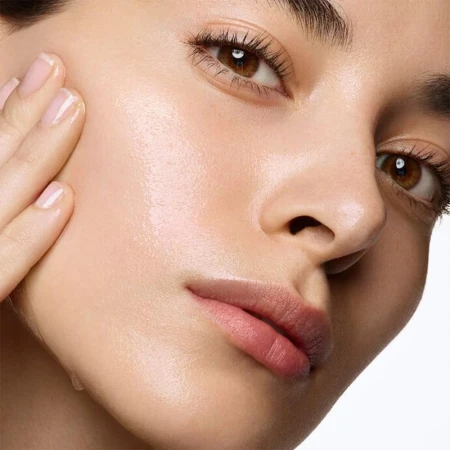 Close-up of a woman's face with clear, hydrated skin and light makeup, emphasizing skincare and beauty, set against a plain white background.