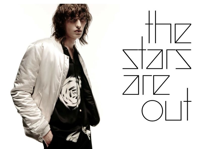 Fashion shot featuring an adult male wearing a satin bomber jacket and patterned shirt on a white background with bold graphic text.