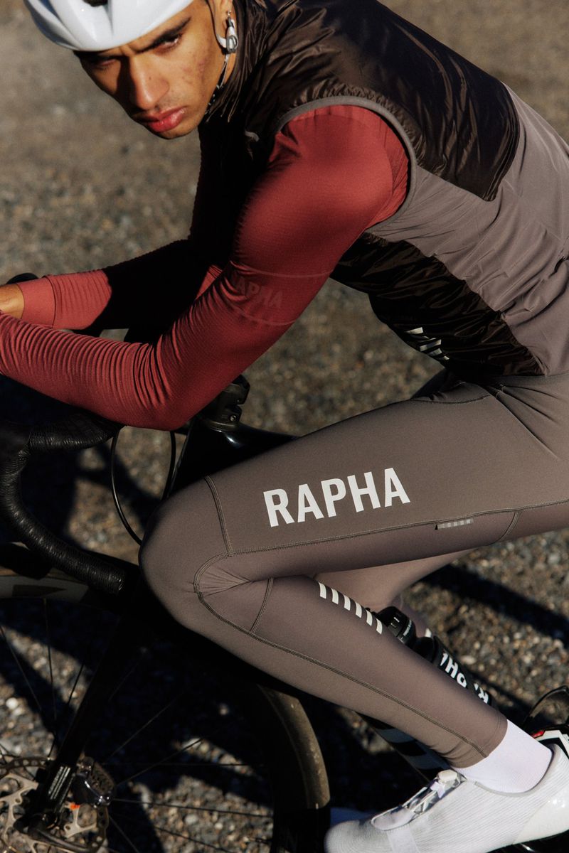 Close-up of a cyclist riding a road bike on a gravel road, wearing cycling gear, helmet, and shoes, with a focus on performance apparel.