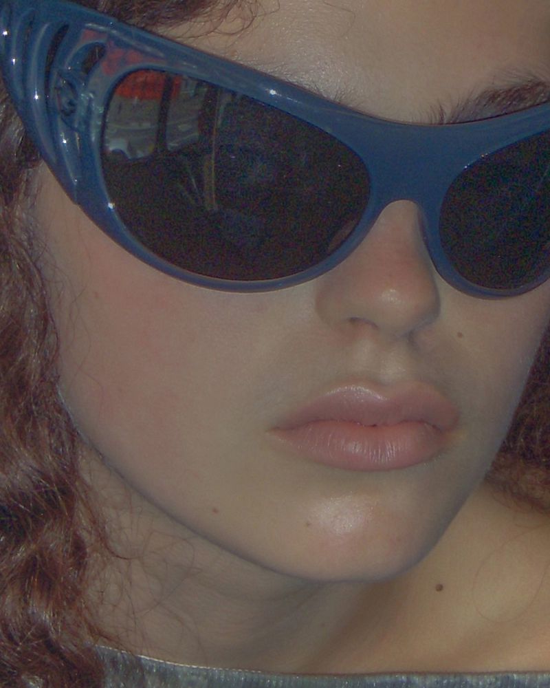 Close-up portrait of model Isla Gaskin wearing dark sunglasses and a top, photographed by Luke Abby.