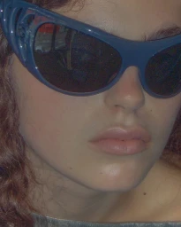 Close-up portrait of model Isla Gaskin wearing dark sunglasses and a top, photographed by Luke Abby.