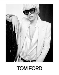 Model wearing dark rectangular sunglasses and a white tailored suit jacket leaning against a person in black for Tom Ford.