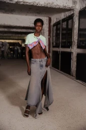 Model wearing a cropped light green t-shirt and an asymmetric slit denim maxi skirt backstage at Y/Project SS24.