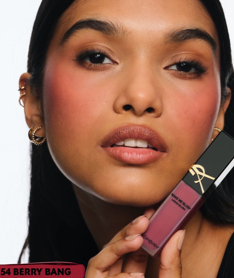 Close-up shot of a woman with rosy cheeks and makeup, holding a liquid blush product in her hand. Beauty and cosmetics advertising.