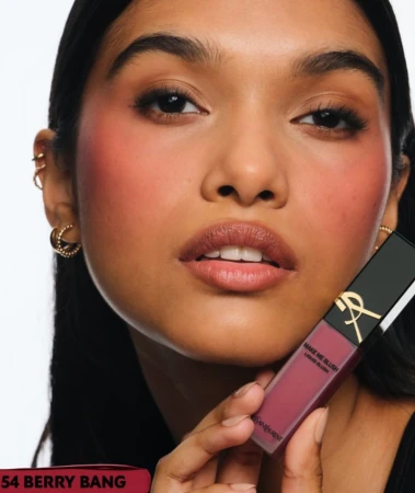 Close-up shot of a woman with rosy cheeks and makeup, holding a liquid blush product in her hand. Beauty and cosmetics advertising.