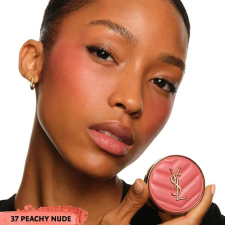 Close-up of a woman wearing blush and holding a compact of blush in her hand, showcasing makeup and beauty products.