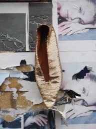 A shimmering gold sequin flat shoe placed vertically against a layered background of torn vintage magazine pages featuring portraits.
