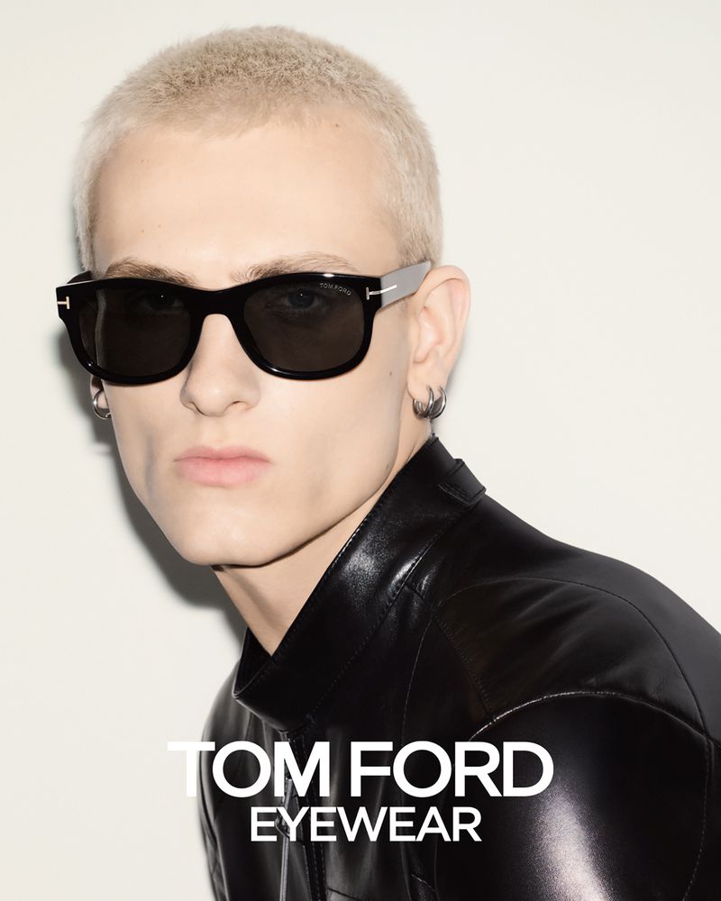 Man wearing Tom Ford sunglasses and a black leather jacket against a white background in a studio shot, advertising eyewear.