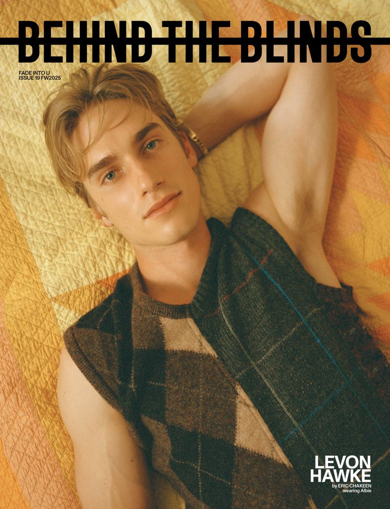 Magazine cover featuring a young adult male model lying on a patterned bed wearing an argyle sweater vest, with the title 'Behind the Blinds'.