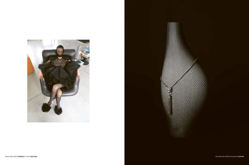 Woman in a black dress sits in a black chair and a dotted bag-shaped vase is against a black background in a studio setting.